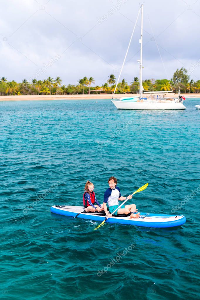 Father and daughter kayaking at tropical ocean