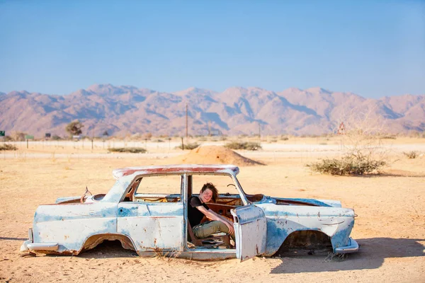 Nastolatek Siedzący Opuszczonym Zabytkowym Samochodzie Pobliżu Stacji Benzynowej Solitaire Namibii — Zdjęcie stockowe