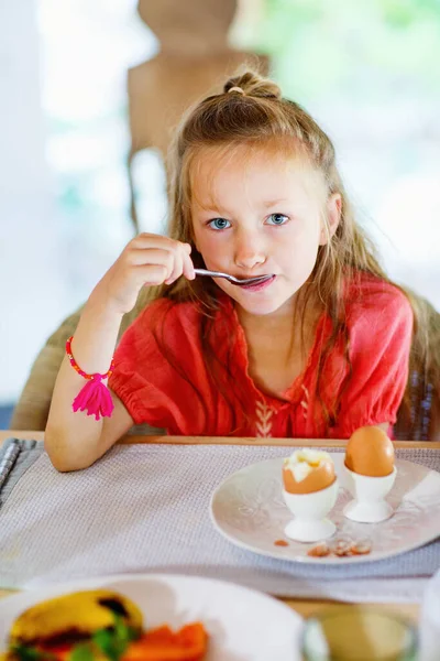 可爱的小女孩在餐馆吃煮熟的鸡蛋当早餐 — 图库照片