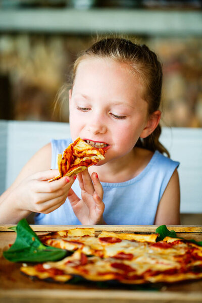 Adorable little girl eating pizza for lunch