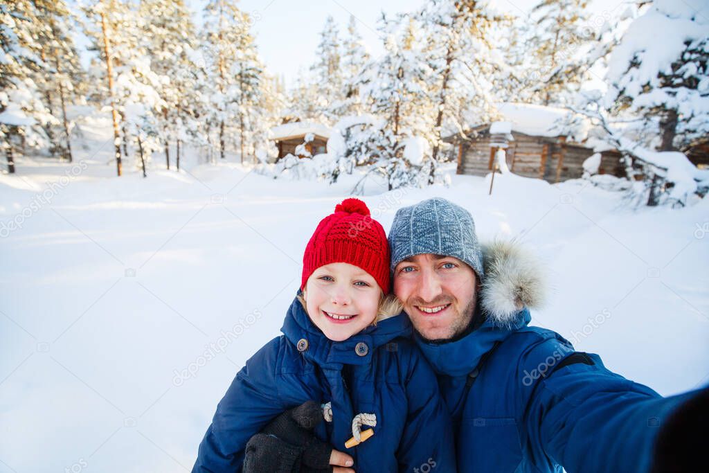 Family of father and his adorable little daughter outdoors on beautiful winter snowy day