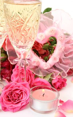 Pembe güller ve beyaz zemin üzerine bir bardak şampanya