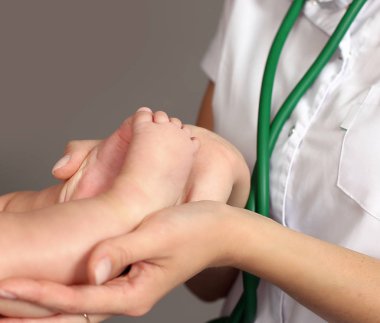 bir doktor bir çocuğun ayak tutan eller