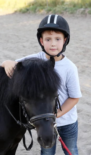 Een Jongen Een Helm Een Zwart Pony — Stockfoto