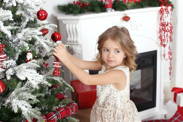 little girl hanging a toy on a branch