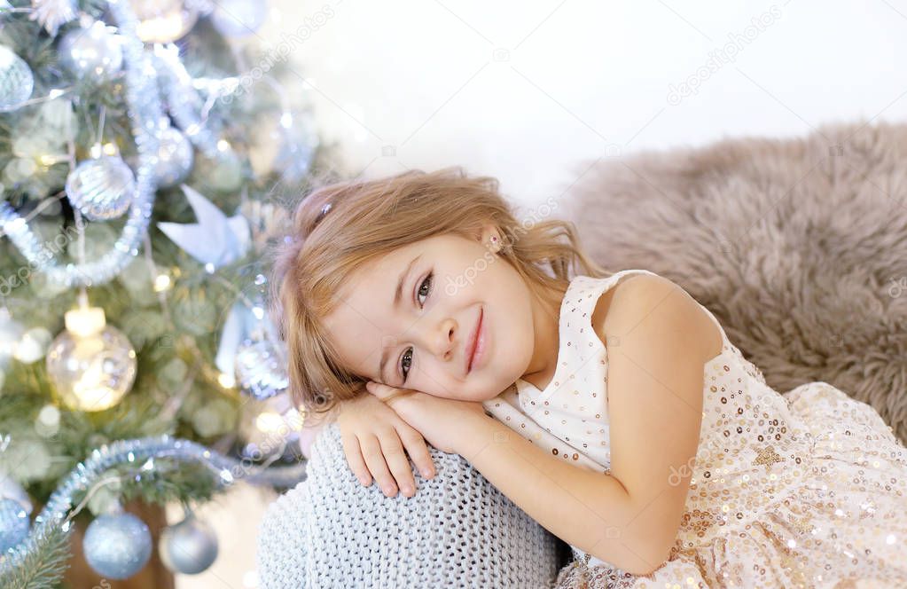 Cute blonde girl in dress at Christmas tree