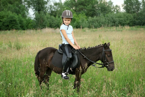 Fille assise en selle sur un petit poney — Photo