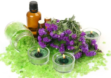 yeşil mumlar, kavanozda deniz tuzu, aroma yağı şişeleri ve menekşe çiçekleri