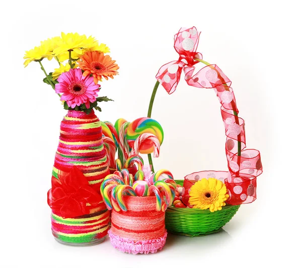 绿色篮子中的圆形彩色糖果和白色背景和鲜花上的罐子 — 图库照片
