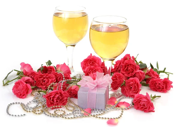 酒杯中的酒 有蝴蝶结的盒子 粉红色的玫瑰和白色背景的珠子 — 图库照片