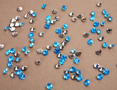 blue shiny stones scattered on beige background clipart