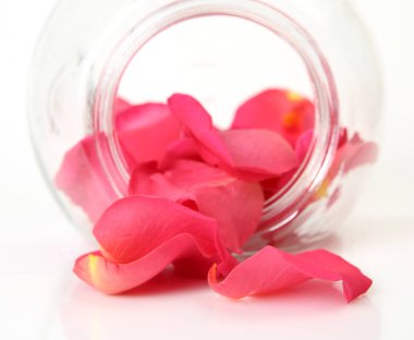 Beyaz arka planda cam kase pembe gül yaprakları