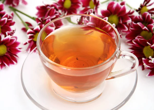 Cup of tea and dark red flowers — Stock Photo, Image