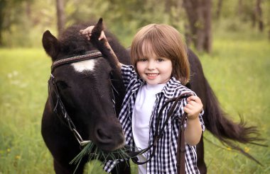 Yeşil çim midilli ile yürüyüş küçük çocuk portresi