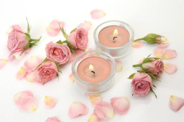 gül yaprakları ve beyaz bir arka plan üzerinde mumlar yakma