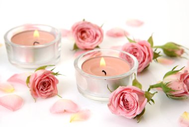 gül yaprakları ve beyaz bir arka plan üzerinde mumlar yakma