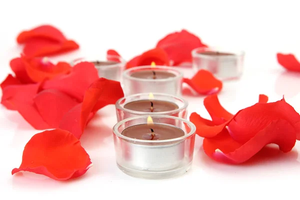 Pétalos de rosa roja sobre un fondo blanco y velas — Foto de Stock