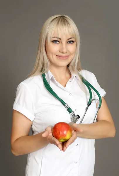 doctor in white coat holding apple in hands