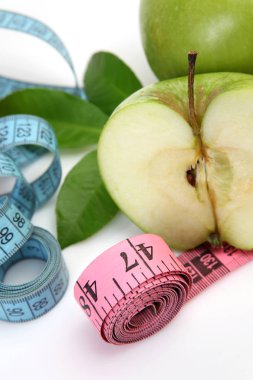 Beyaz arka planda yeşil elma ve mezura.