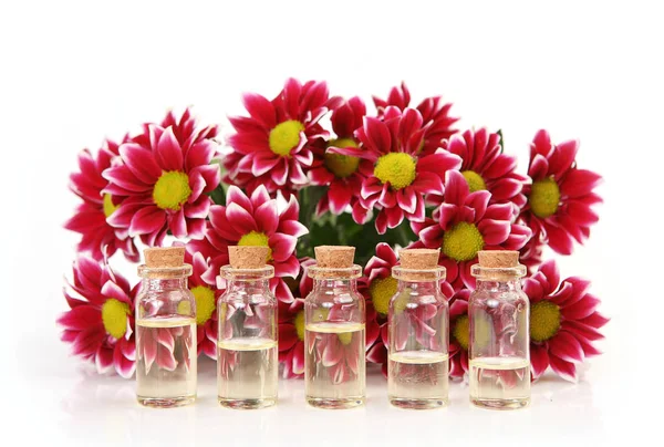 Huile de massage et un bouquet de chrysanthèmes sur un fond blanc — Photo