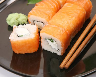 siyah bir tabak üzerinde pirinç ve balık ile rulo