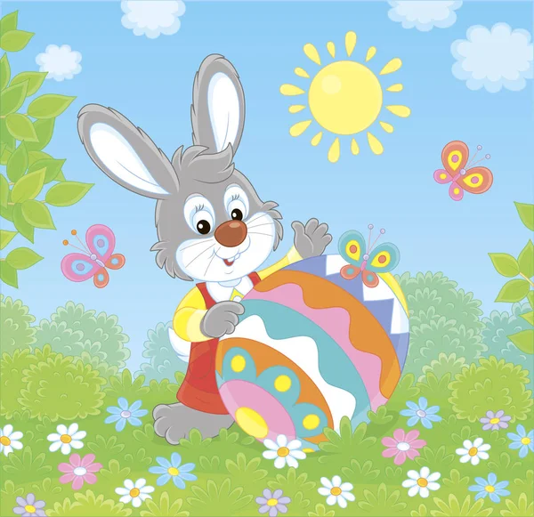 在一个阳光明媚的春日 小复活节兔子和一个装饰五颜六色的大蛋在鲜花和飘落的蝴蝶在绿色的草坪上 矢量插图在卡通风格 — 图库矢量图片