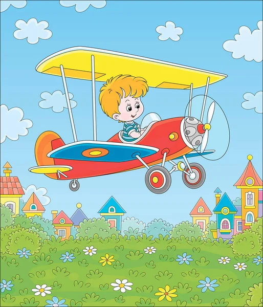 Küçük neşeli çocuk küçük oyuncak uçağını mavi yaz gökyüzünde beyaz bulutların arasında parlak güneşli bir günde renkli kasaba evlerinin yakınındaki yeşil bir parkın üzerinde kullanıyor.
