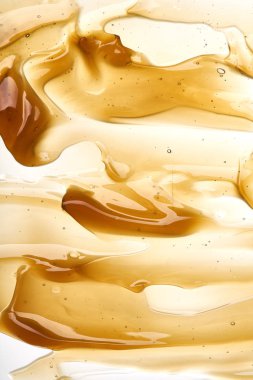 Yüz kremi veya altın şeffaf sarı smear izole üzerinde beyaz arka plan tatlım. Beyaz zemin üzerine altın krem honet doku