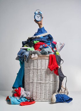 Gri arka plan üzerinde mavi bir çalar saat tutan bir el ile tam Çamaşırhane beyaz hasır sepet