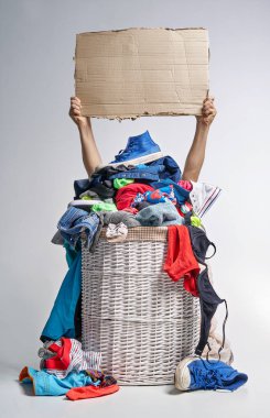 Tam Çamaşırhane gri arka plan üzerinde beyaz hasır sepet. İki el bir karton tablet tutun