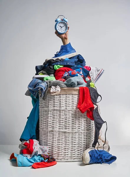 Gri arka plan üzerinde mavi bir çalar saat tutan bir el ile tam Çamaşırhane beyaz hasır sepet