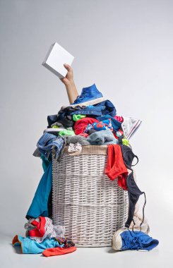 Tam Çamaşırhane gri arka plan üzerinde beyaz hasır sepet. Bir el çamaşır deterjanı ile beyaz bir kutu tutar