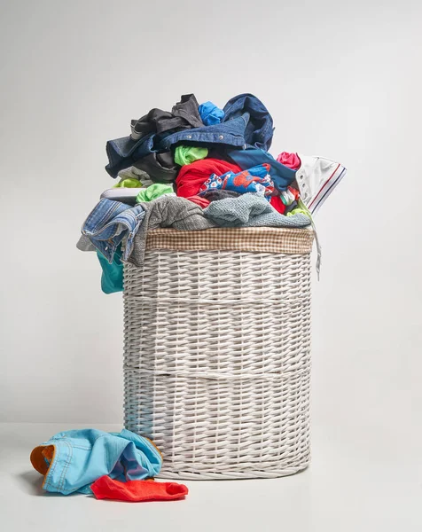 Full laundry white wicker basket on the grey background