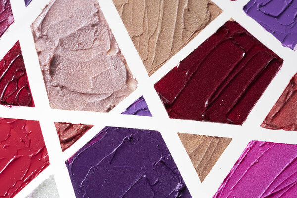 Smears of different colors are made with various cosmetic products isolated on a white background.