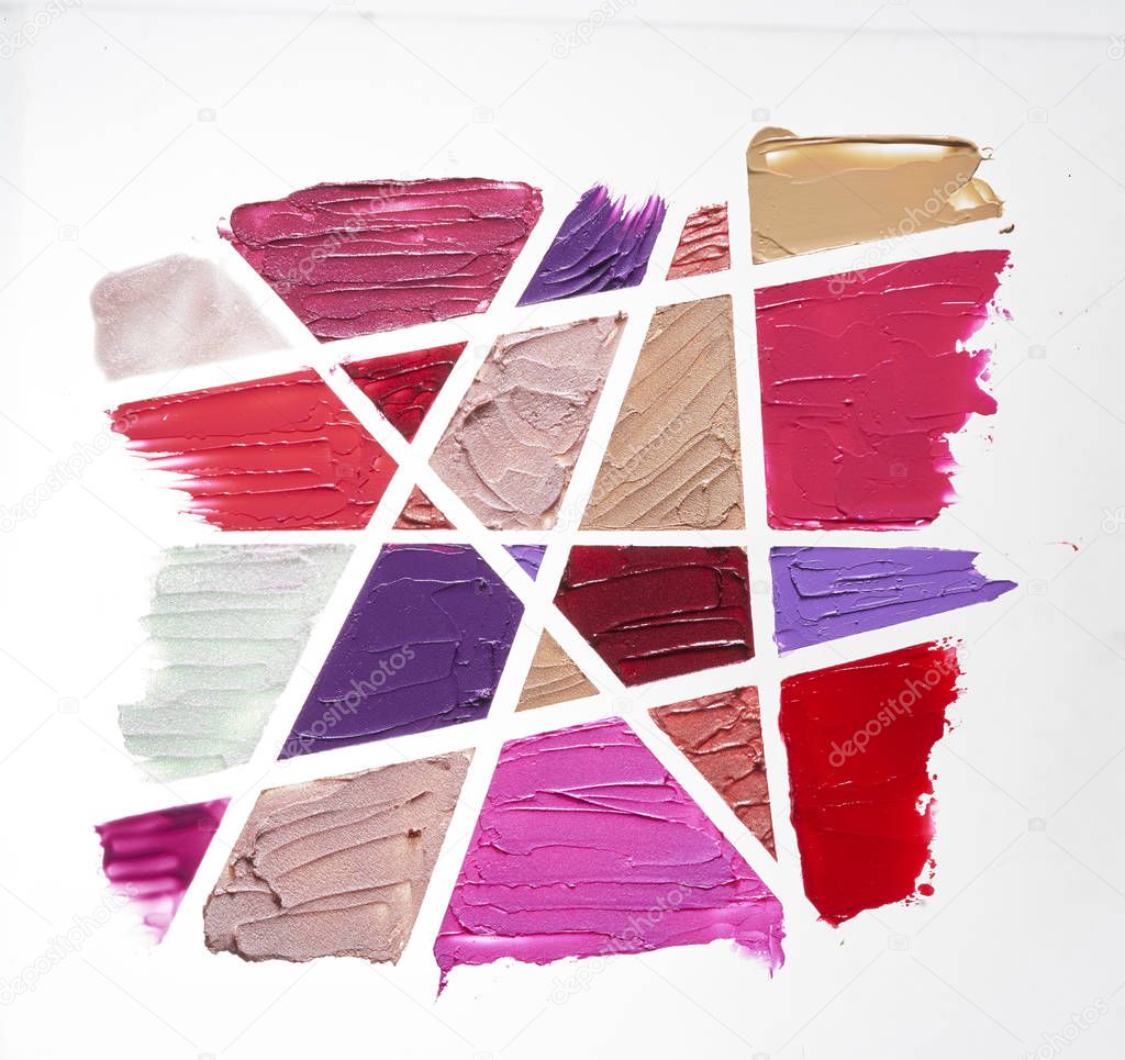 Smears of different colors are made with various cosmetic products isolated on a white background.