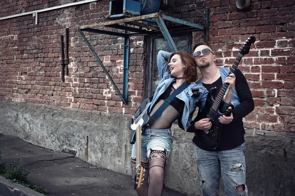 Girl and guy punks on a city street play on guitars