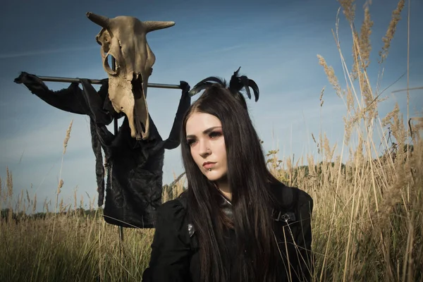 夏のフィールでポールに牛の頭蓋骨の横にあるゴシック様式女の子 — ストック写真