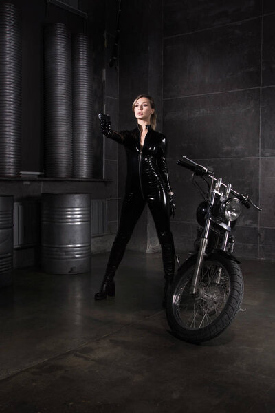 Hit woman. Biker girl in a latex suit with gun in hand