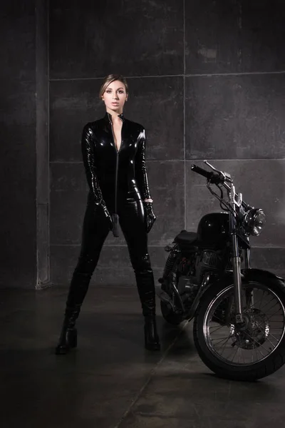 女性をヒットします 手で銃を持つラテックス スーツでバイクに乗る女の子 — ストック写真