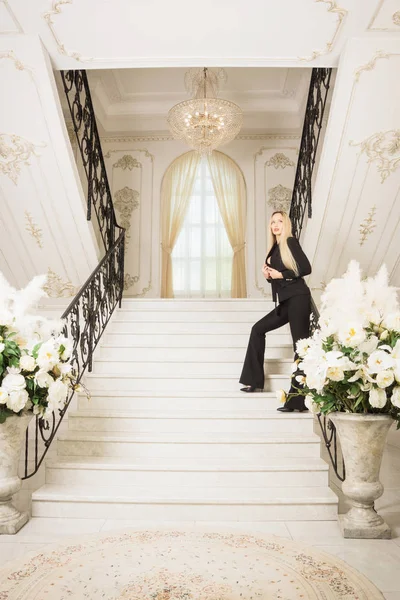 Beautiful young business woman standing on the stairs in a luxurious interior