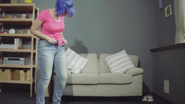 Mooi meisje probeert te zetten op jeans — Stockvideo
