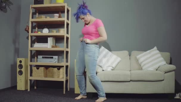 Красивая девушка пытается надеть джинсы — стоковое видео