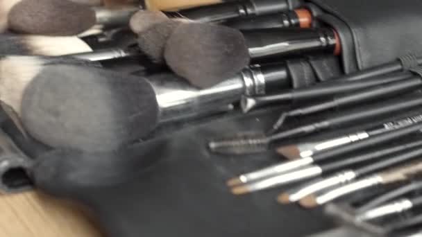Ahşap arka plan üzerinde dağınık makyaj için fırçalar kümesi — Stok video