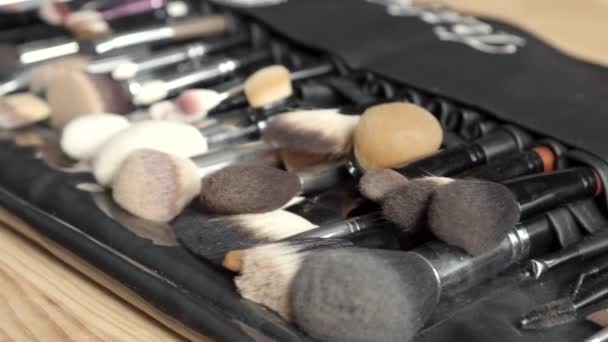 Set de pinceles para maquillaje esparcidos sobre fondo de madera — Vídeo de stock