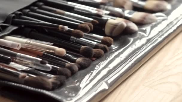 Set de pinceles para maquillaje esparcidos sobre fondo de madera — Vídeos de Stock