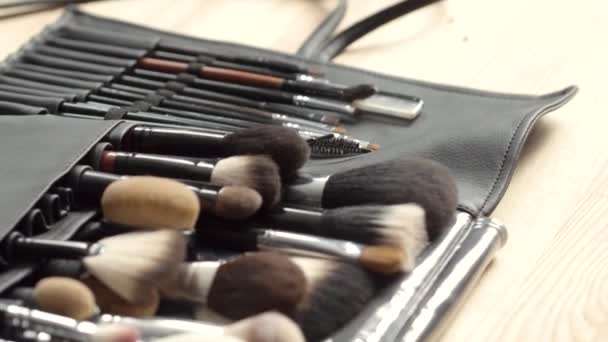 Set de pinceles para maquillaje esparcidos sobre fondo de madera — Vídeo de stock