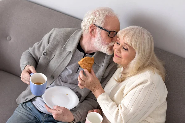 Aged couple having coffee on couch. — Stock Photo, Image