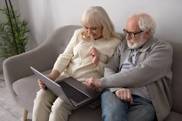Coppia anziana con laptop sul divano . — Foto Stock