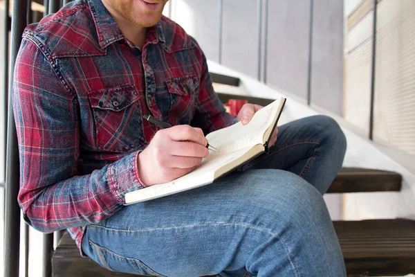 Homem escrevendo em seu caderno em casa . — Fotografia de Stock