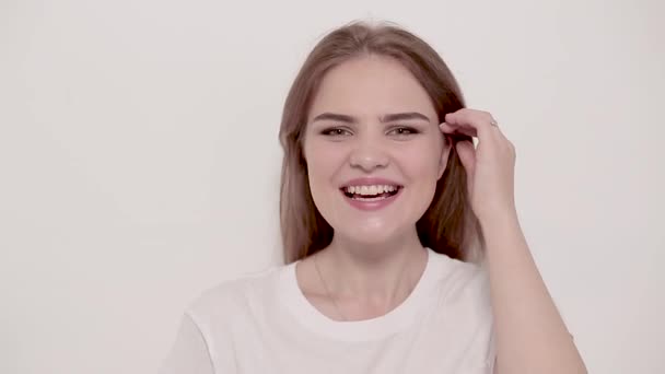 Junge Frau posiert und lächelt auf weißem Hintergrund — Stockvideo